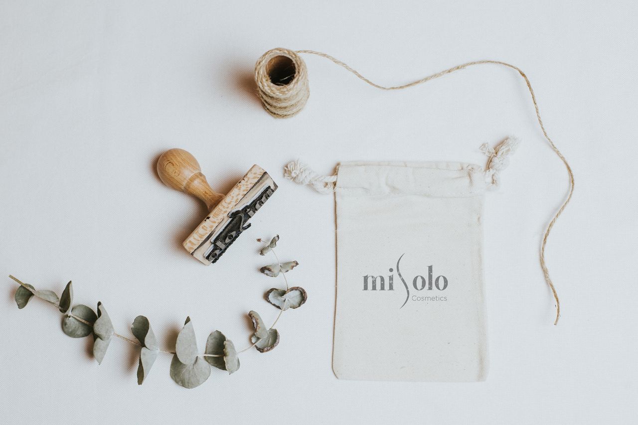 Organic cosmetic packaging with natural elements and stamp on white background.